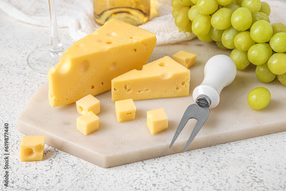 Board with tasty Swiss cheese on light background