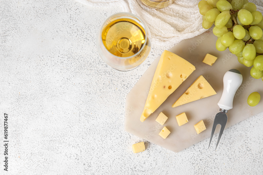 Board with tasty Swiss cheese and and glass of wine on light background