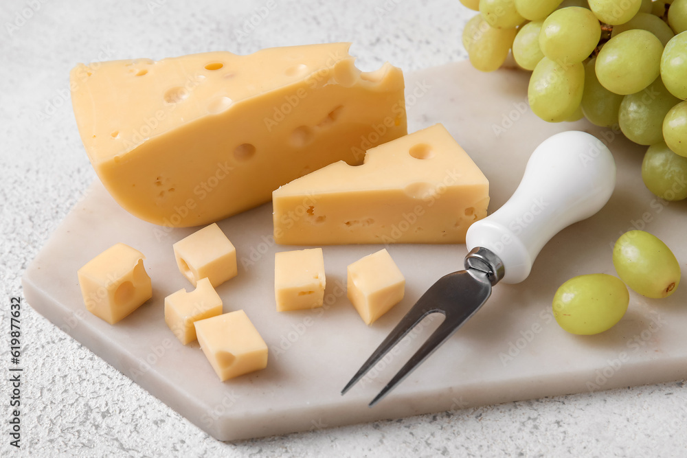 Board with tasty Swiss cheese on light background