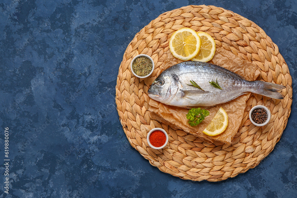 Raw dorado fish with lemon and spices on blue background