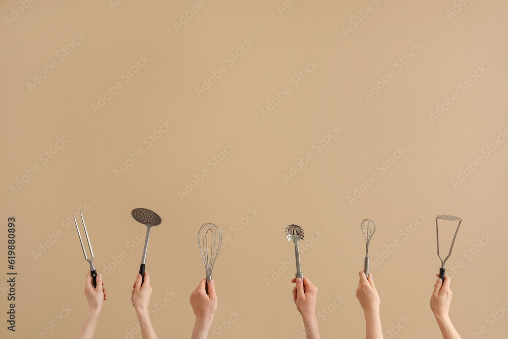 Female and male hands holding different kitchen utensils on brown background