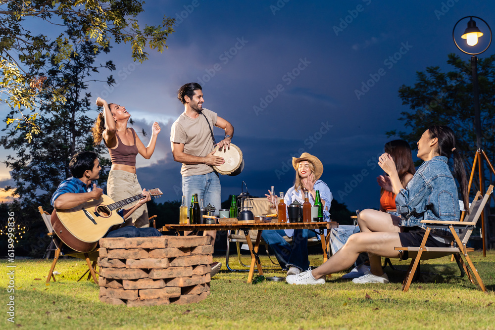 Group of diverse friend having outdoors camping party together in tent. 