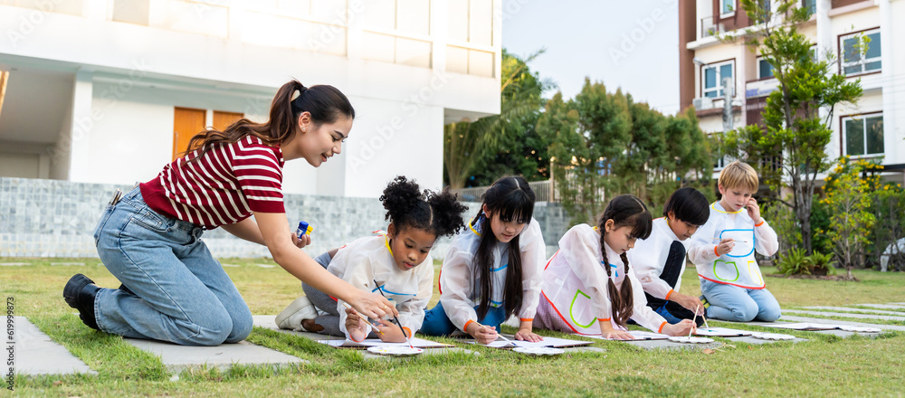 Group of student coloring on painting board outdoors in school garden.