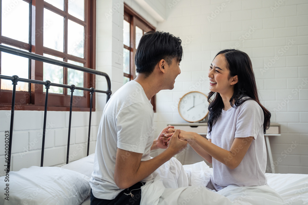 Asian new marriage couple sitting on bed and looking at each other. 