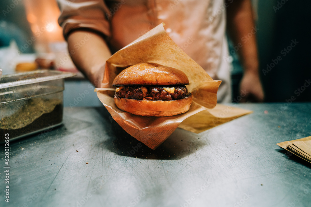 Chef holding hamburger with cheese in a food truck