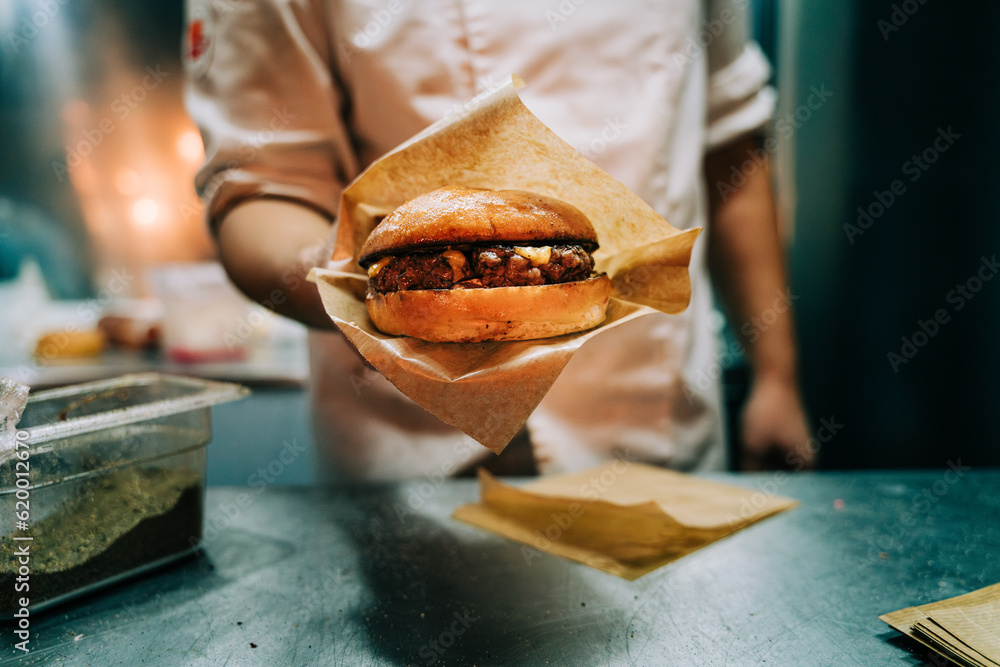 Chef holding hamburger with cheese in a food truck