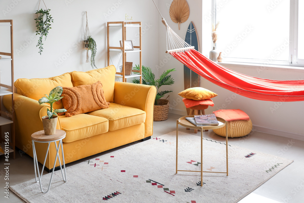 Interior of stylish living room with red hammock, yellow sofa and coffee table