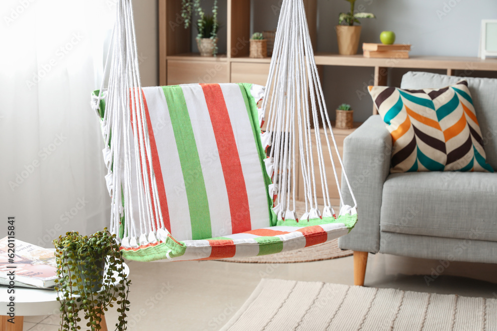 Interior of stylish living room with striped hammock and grey sofa