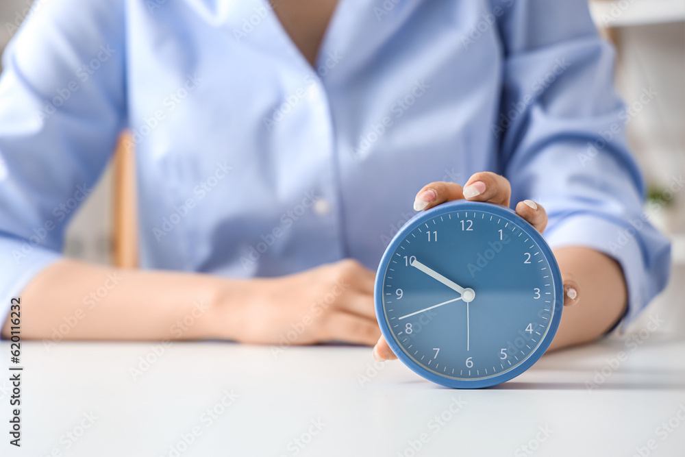 Businesswoman touching alarm clock on table, closeup. Time management concept