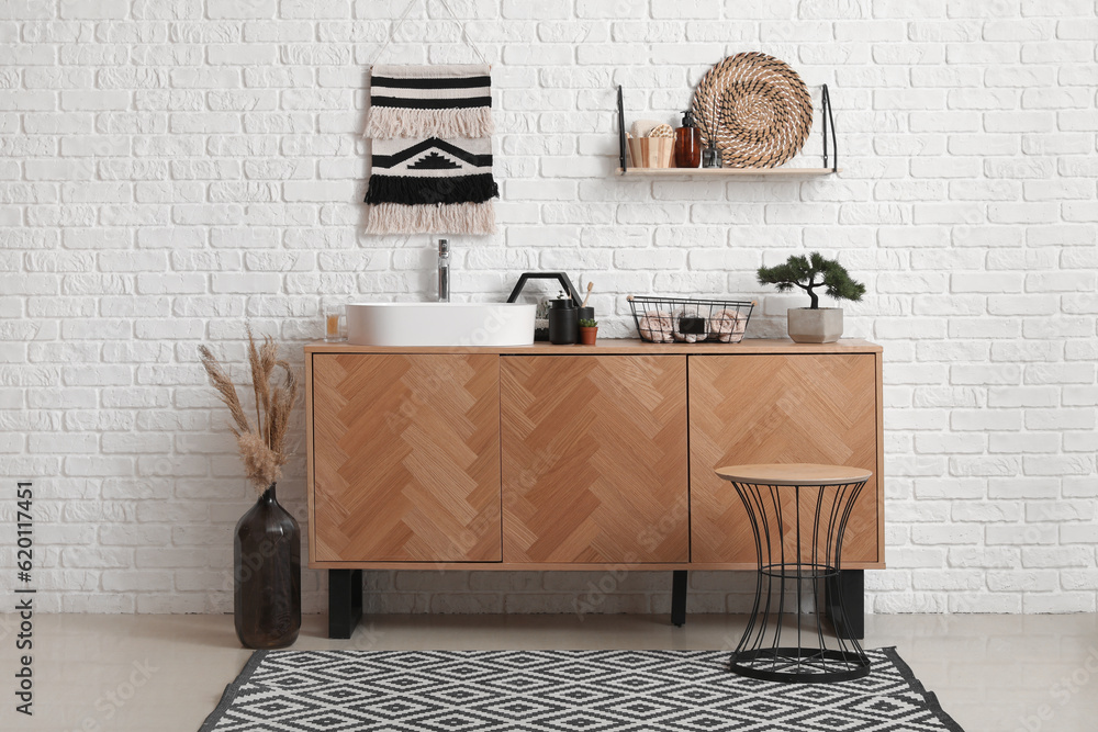 Interior of bathroom with sink bowl and bath accessories on wooden cabinet