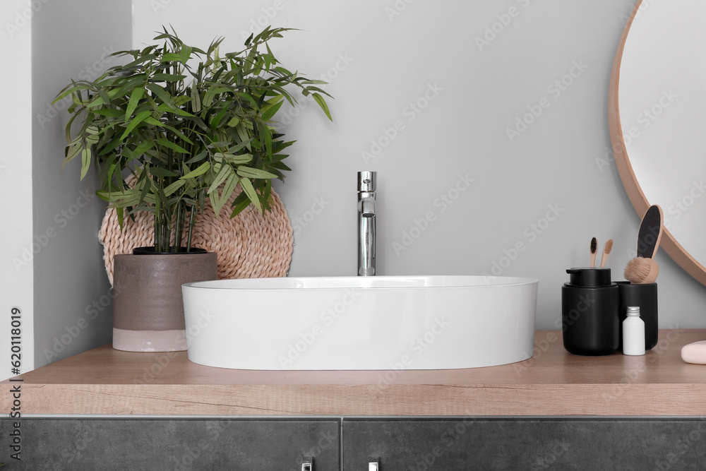 Sink bowl and bath accessories on wooden counter in bathroom