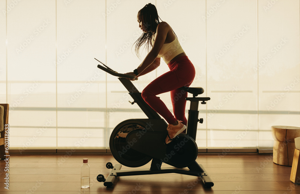 Indoor cycling for fitness: Young African woman on stationary bike