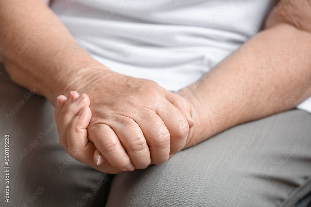 Hands of senior woman sitting at home, closeup