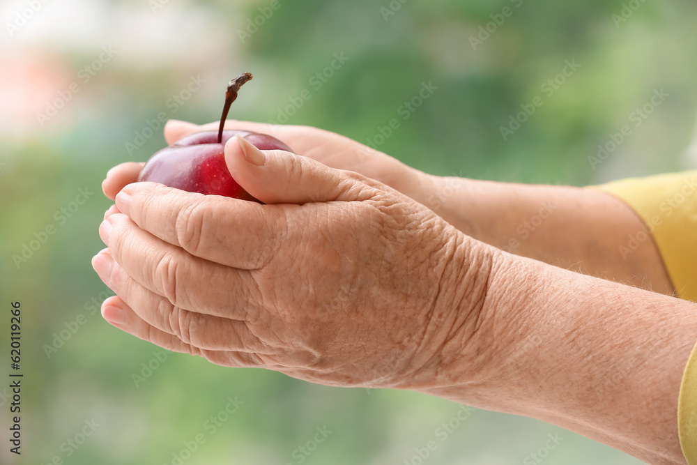 Senior woman with apple at home, closeup