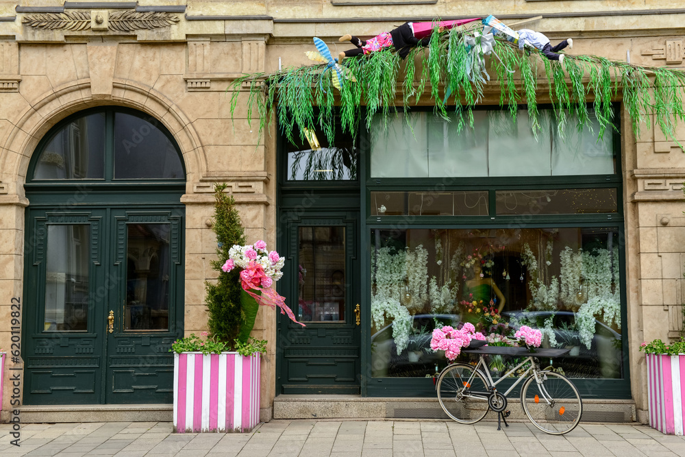 Stylish bicycle with peonies flowers near shop entrance on city street