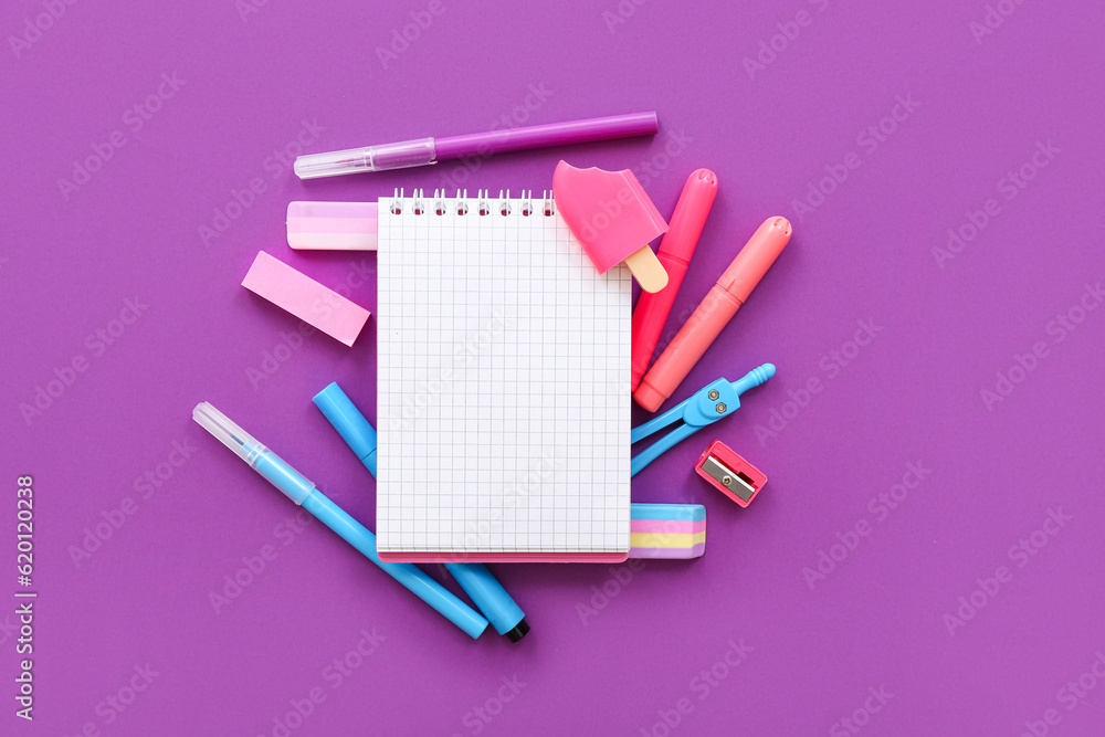 Blank notebook with different stationery on purple background