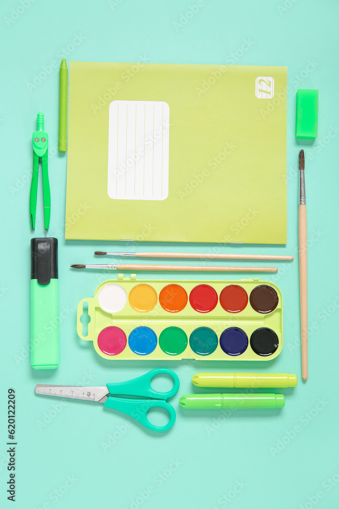 Notebook with different stationery on turquoise background