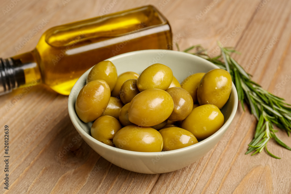 Bowl with ripe olives on wooden background