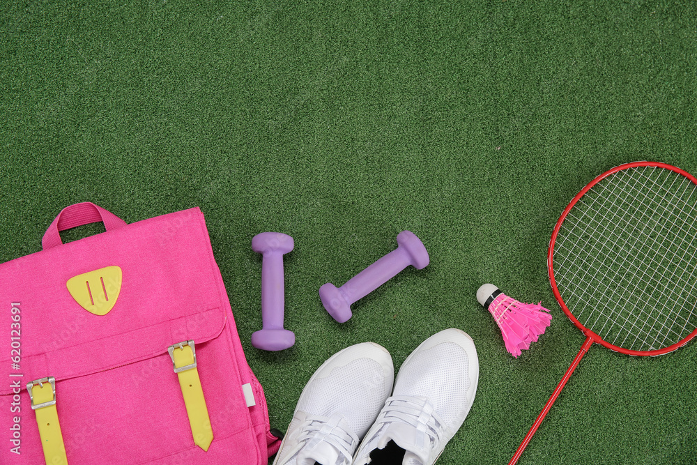 Backpack with sneakers, badminton shuttlecock and dumbbells on color background