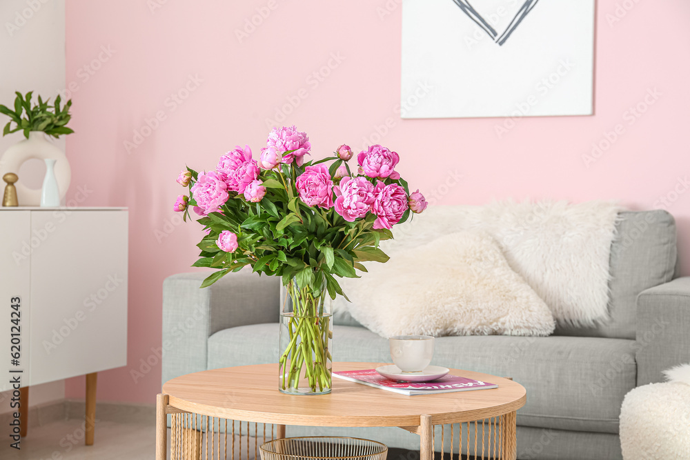 Vase of pink peonies on coffee table with couch in living room