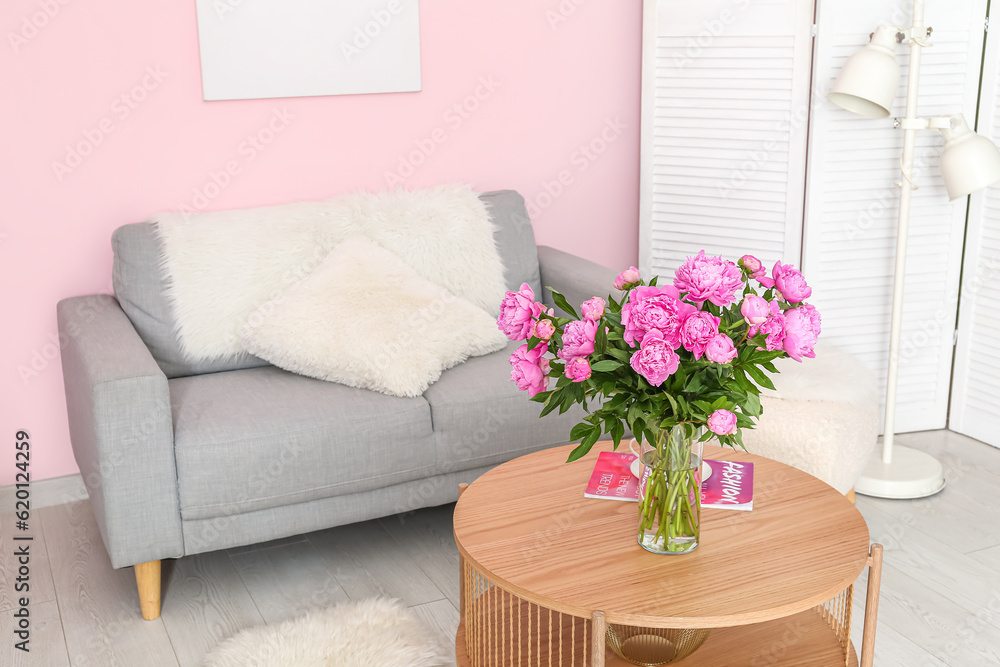 Vase of pink peonies on coffee table with couch in living room