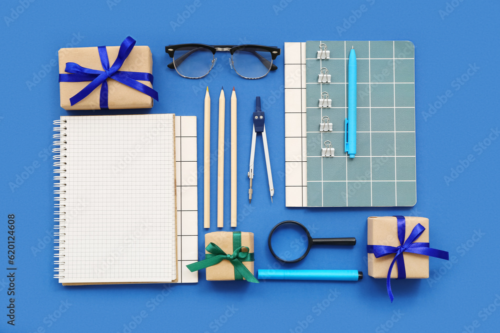 Gift boxes with magnifier, eyeglasses and different stationery on blue background