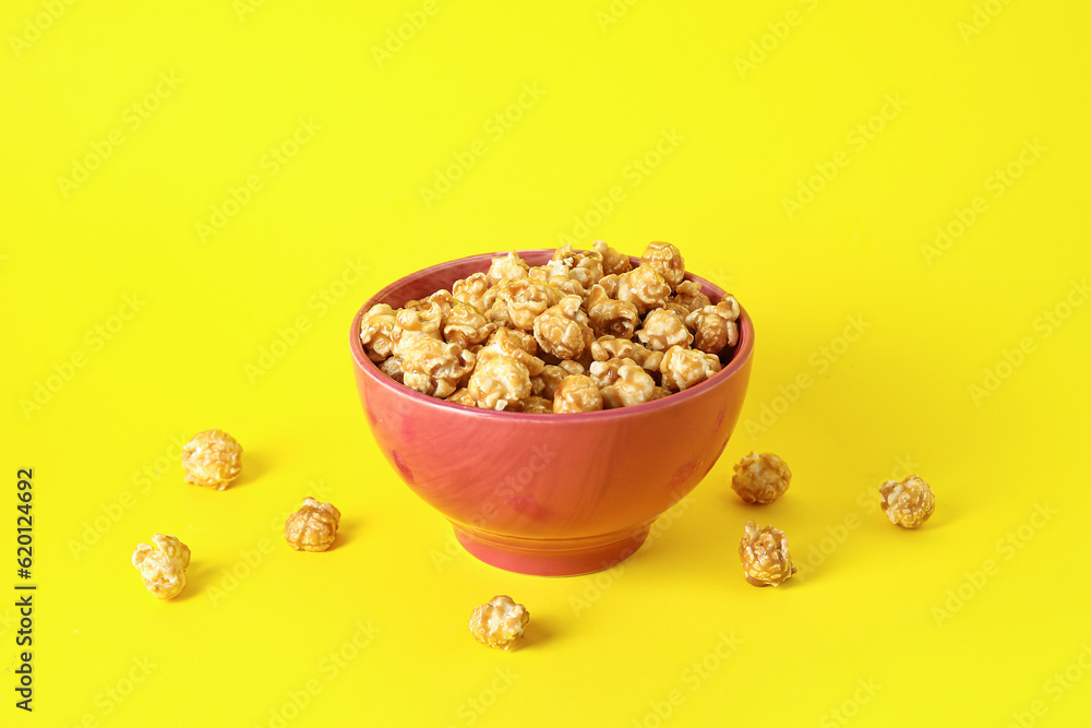 Bowl with tasty popcorn on yellow background