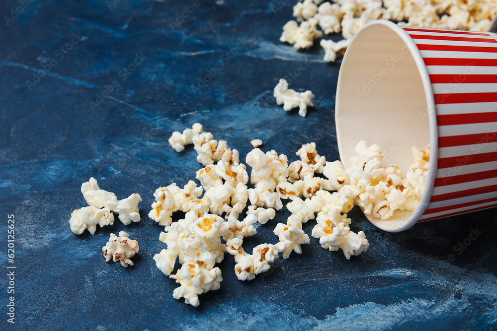 Bucket with tasty popcorn on blue background