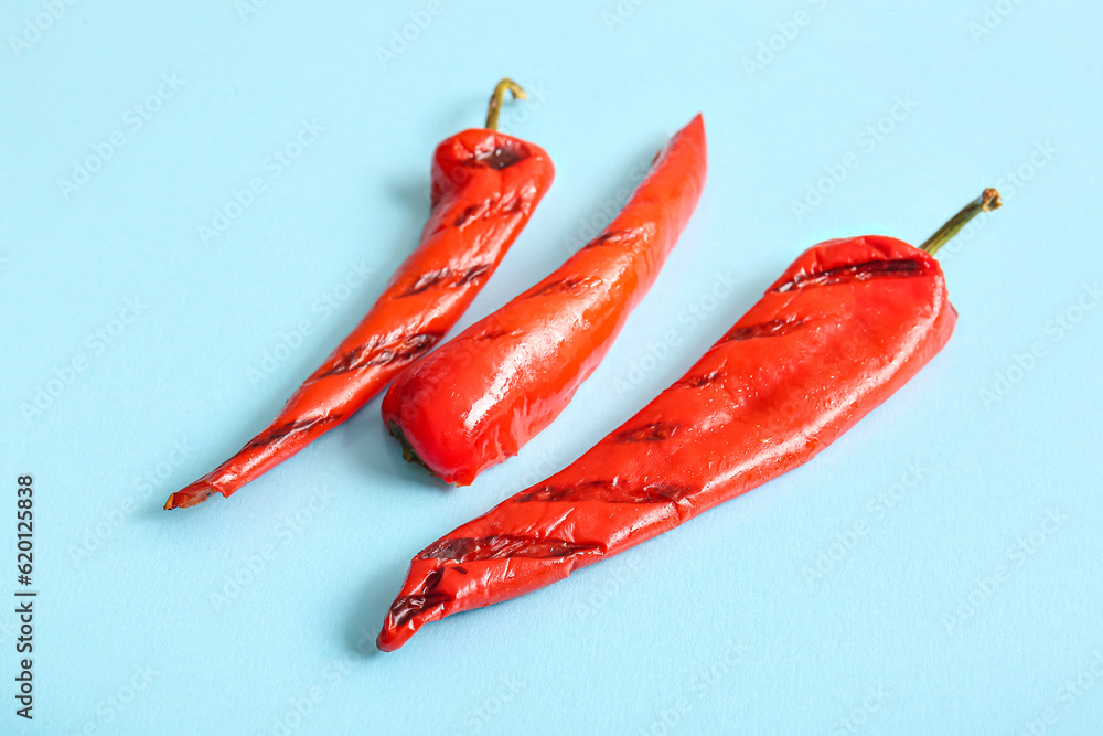 Tasty grilled chili pepper on blue background