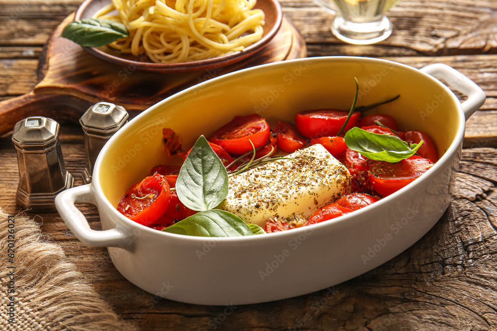 Baking dish with tasty tomatoes and feta cheese on wooden background