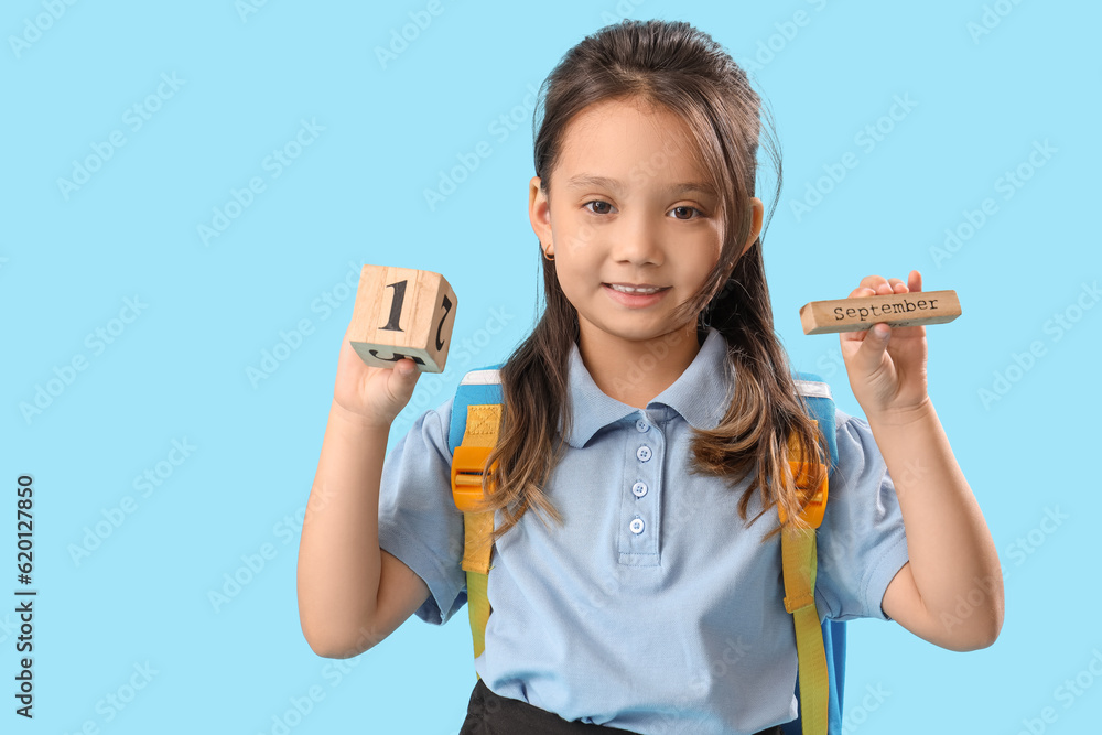 Little schoolgirl with calendar on light blue background