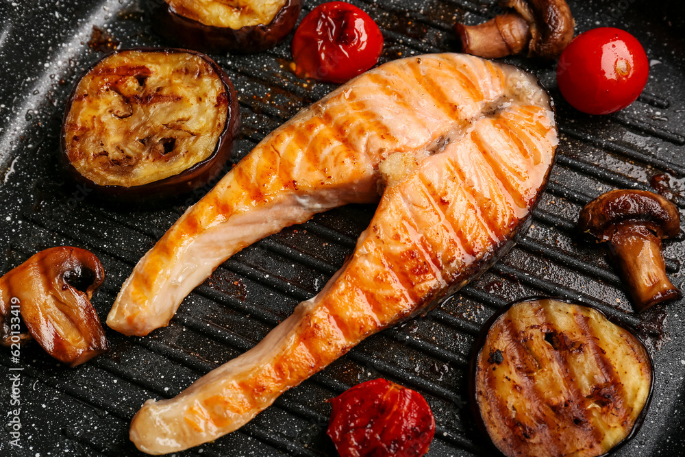 Tasty grilled salmon steak with vegetables in frying pan, closeup