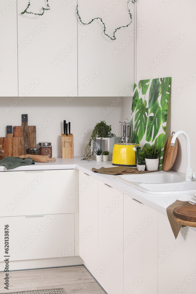 Interior of modern kitchen with white counters and utensils