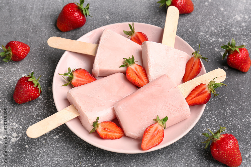 Plate with sweet strawberry ice-cream popsicles on grey background