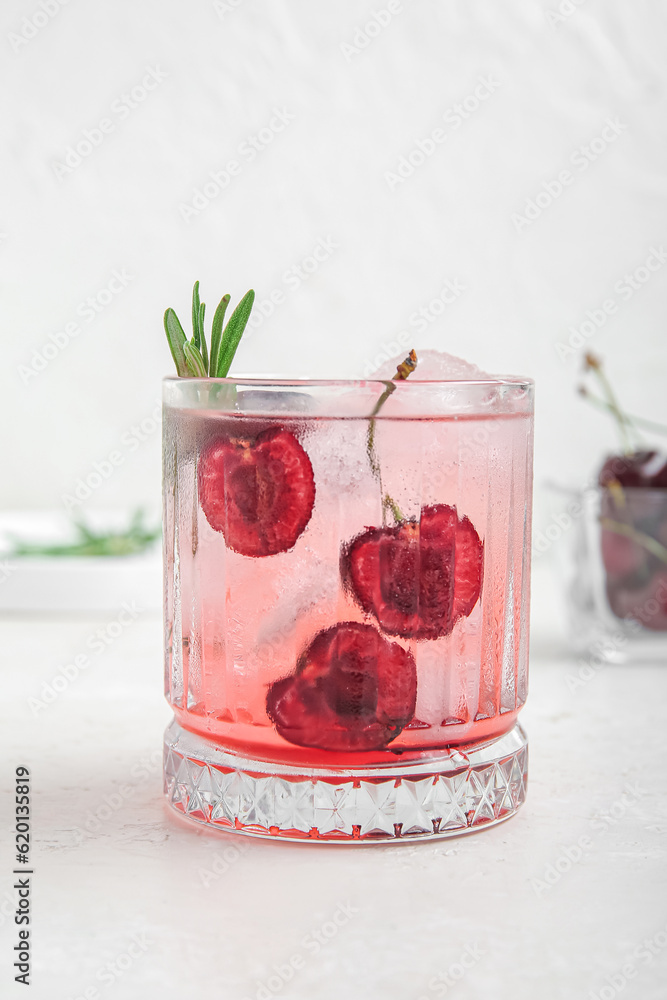 Glass of tasty cherry lemonade with rosemary on white background