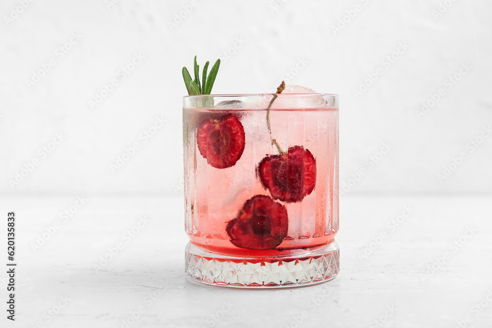 Glass of tasty cherry lemonade with rosemary on white background