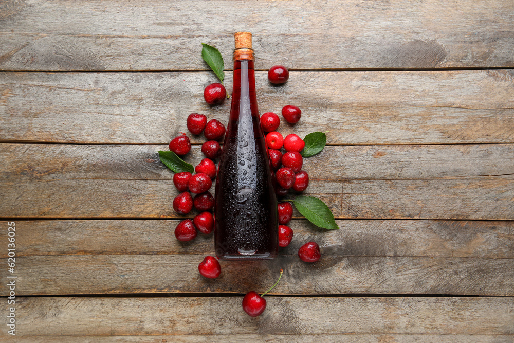 Bottle with sweet cherry liqueur on wooden background