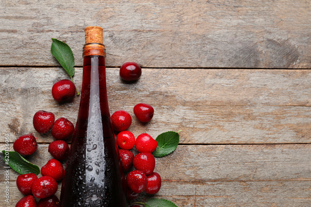 Bottle with sweet cherry liqueur on wooden background