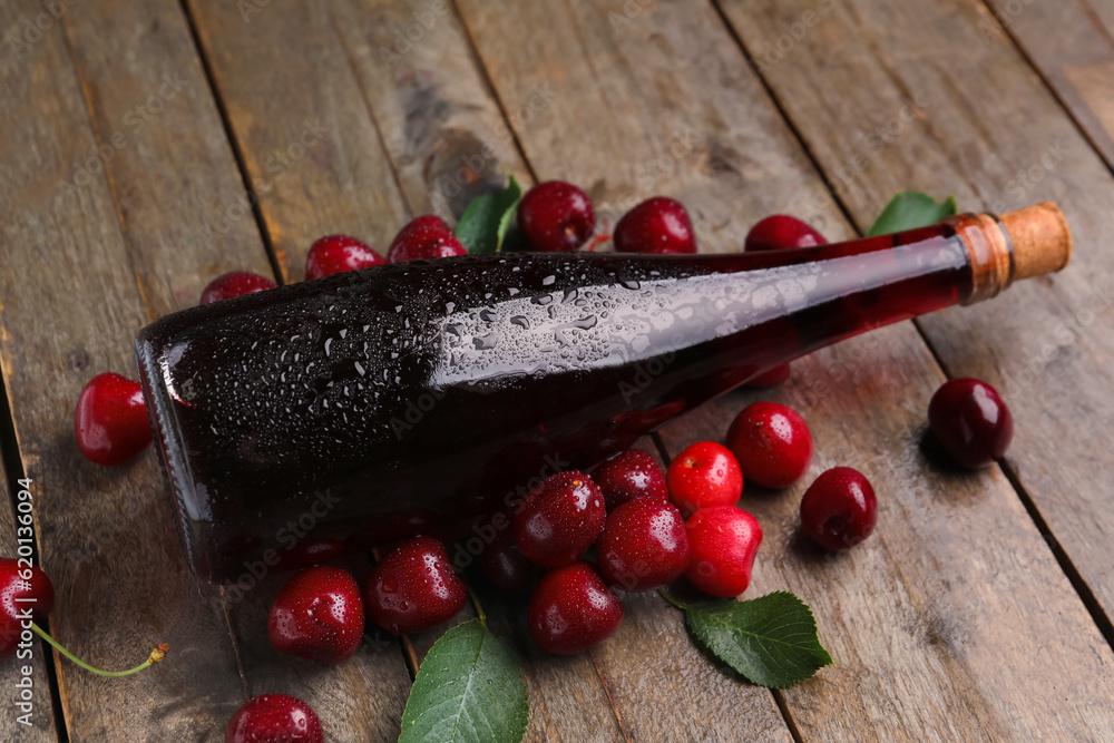 Bottle with sweet cherry liqueur on wooden background