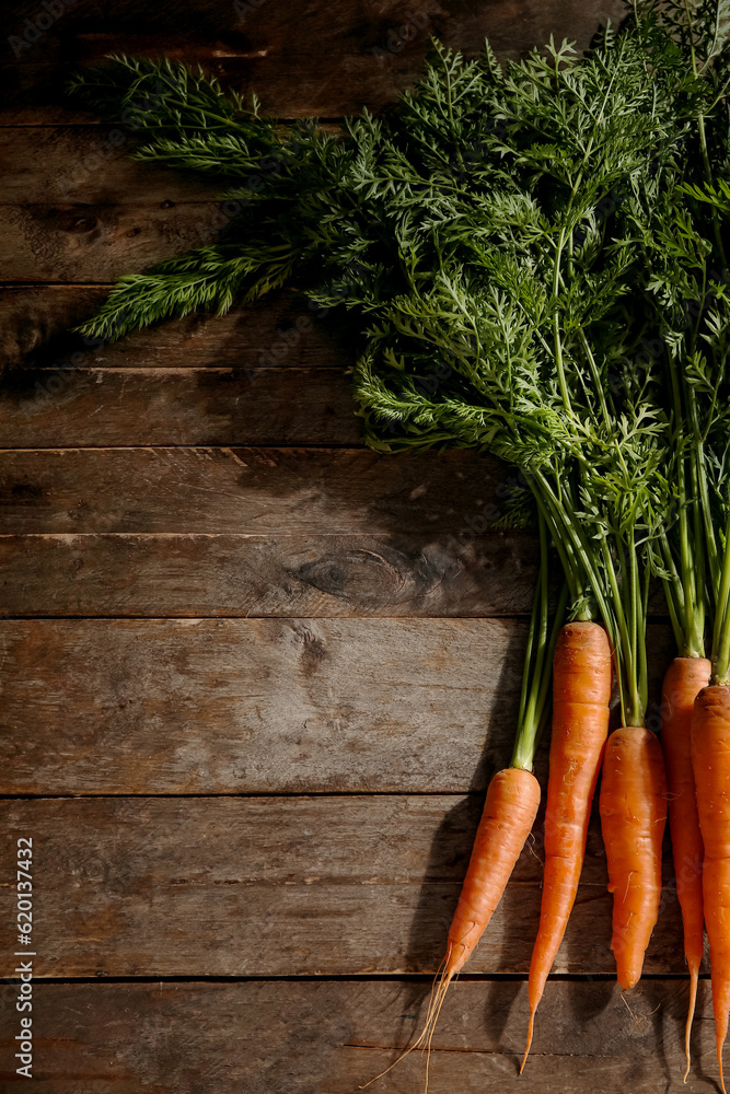 Fresh carrots with leaves on wooden background