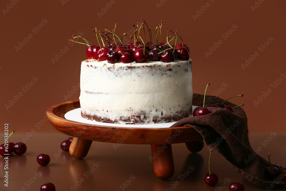 Wooden stand with tasty cherry cake on red background