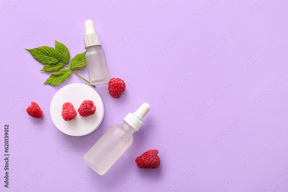 Bottles of cosmetic raspberry oil on lilac background