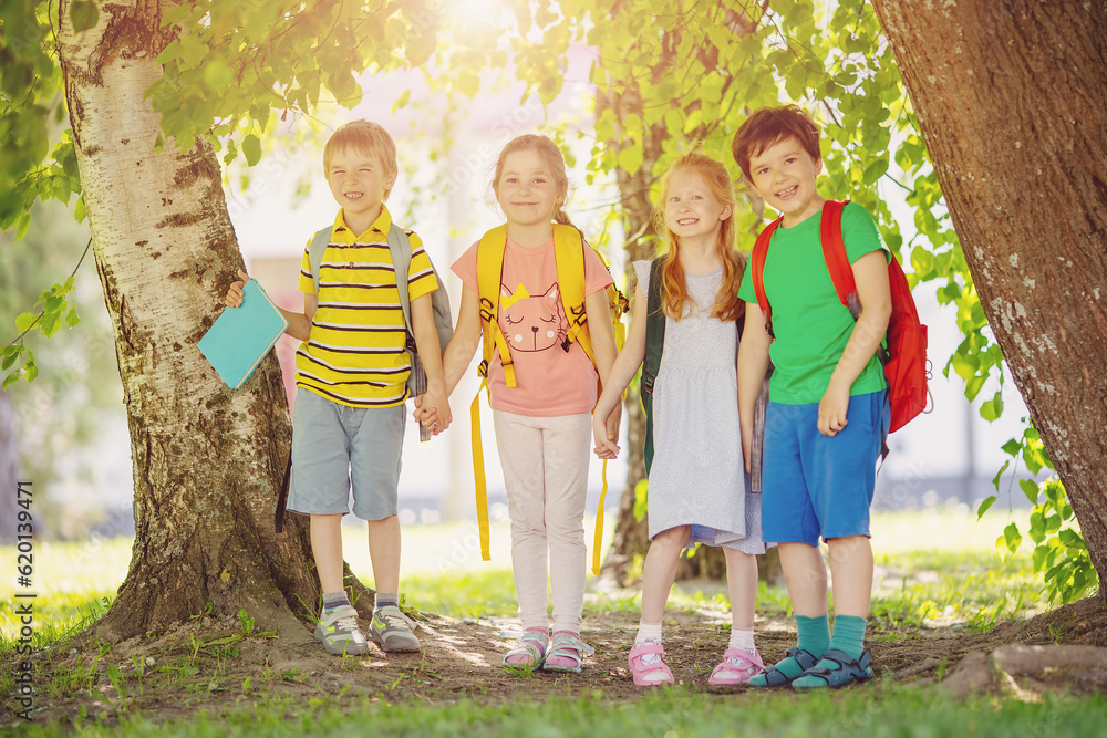 Group of children standing with backpacks near the school.