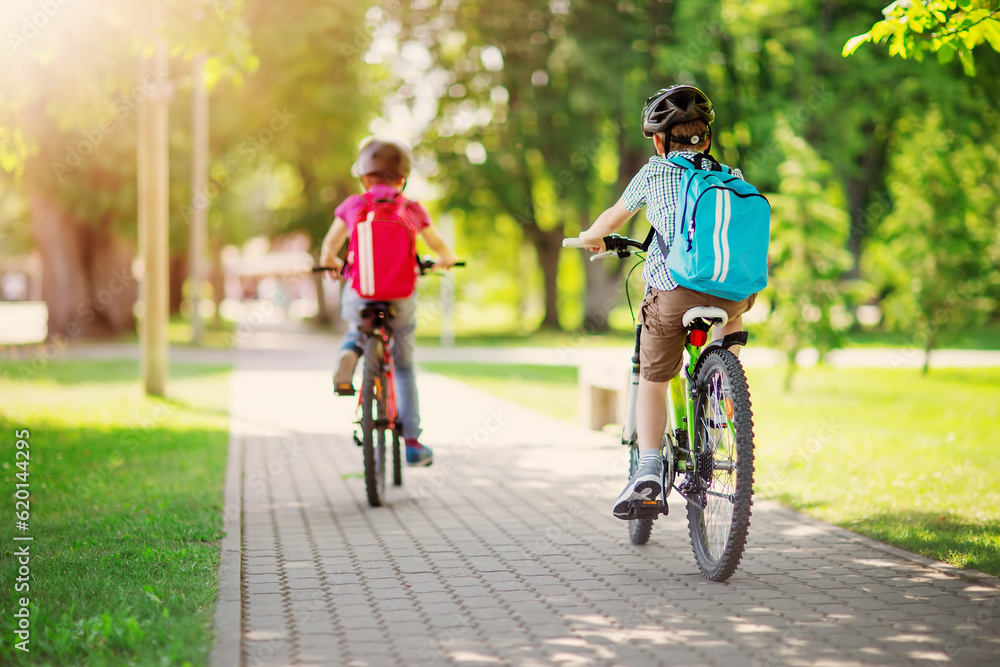 Two boys with backpacks on bicycles going to school.