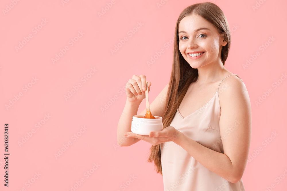 Pretty young woman with sugaring paste on pink background