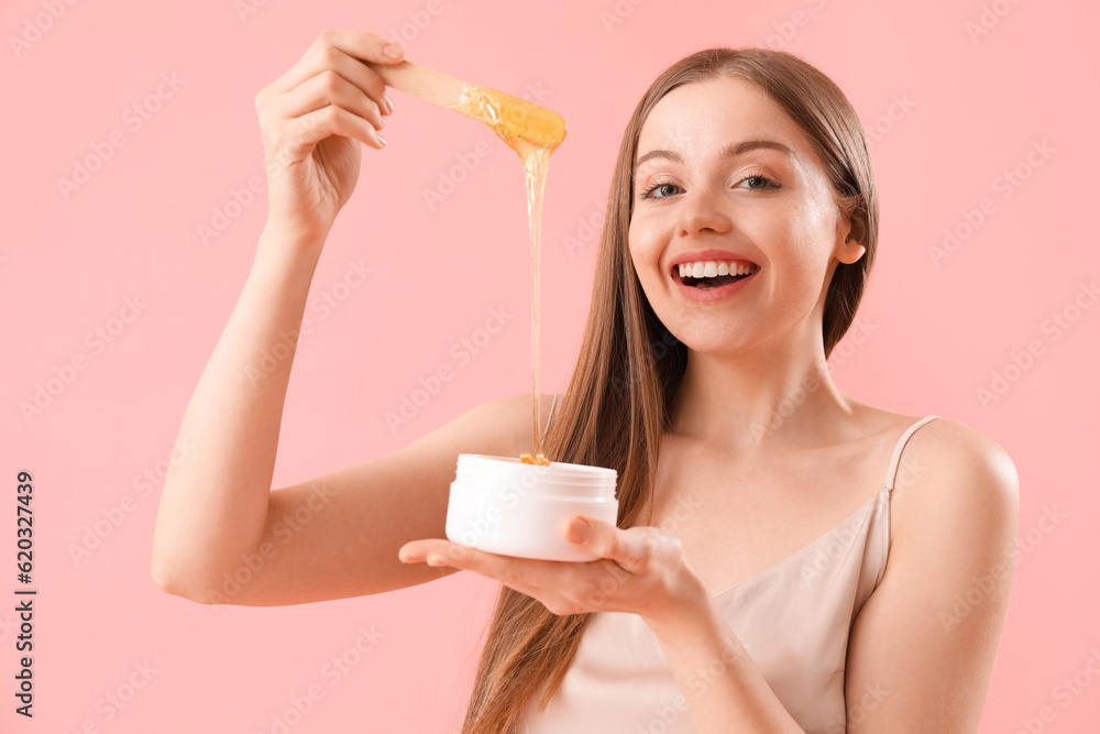 Pretty young woman with sugaring paste on pink background