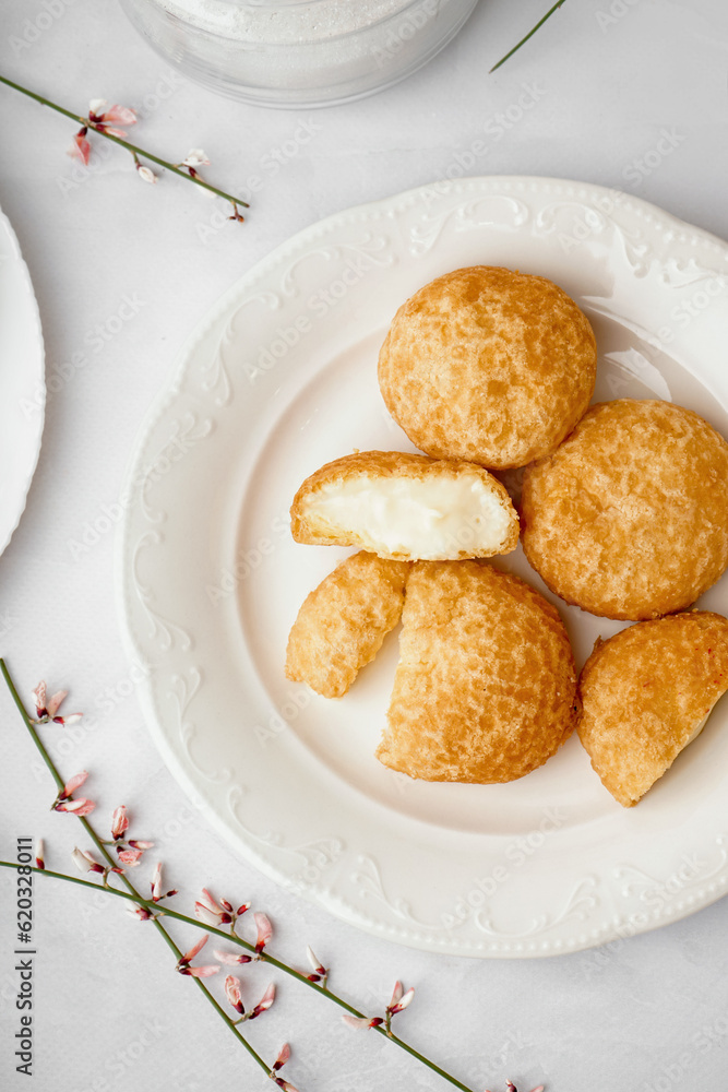 Plate with tasty choux dessert on light background