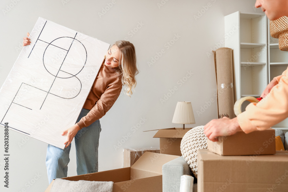 Young couple packing things in room on moving day