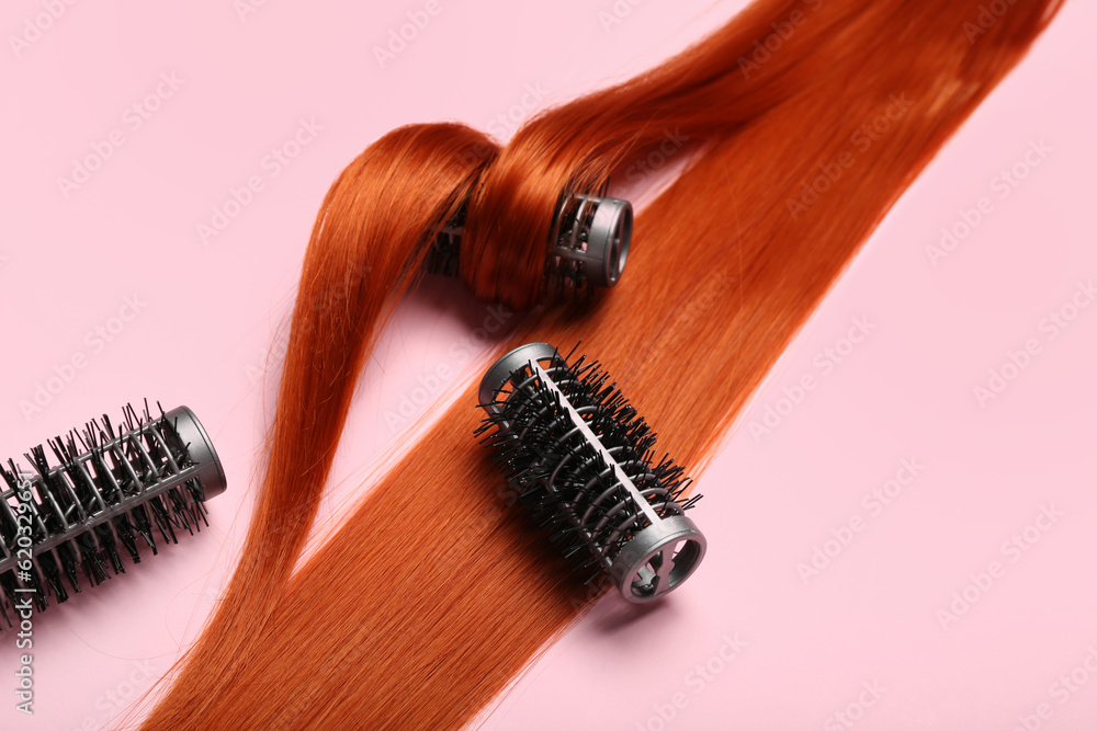 Ginger hair strand with curlers on pink background, closeup