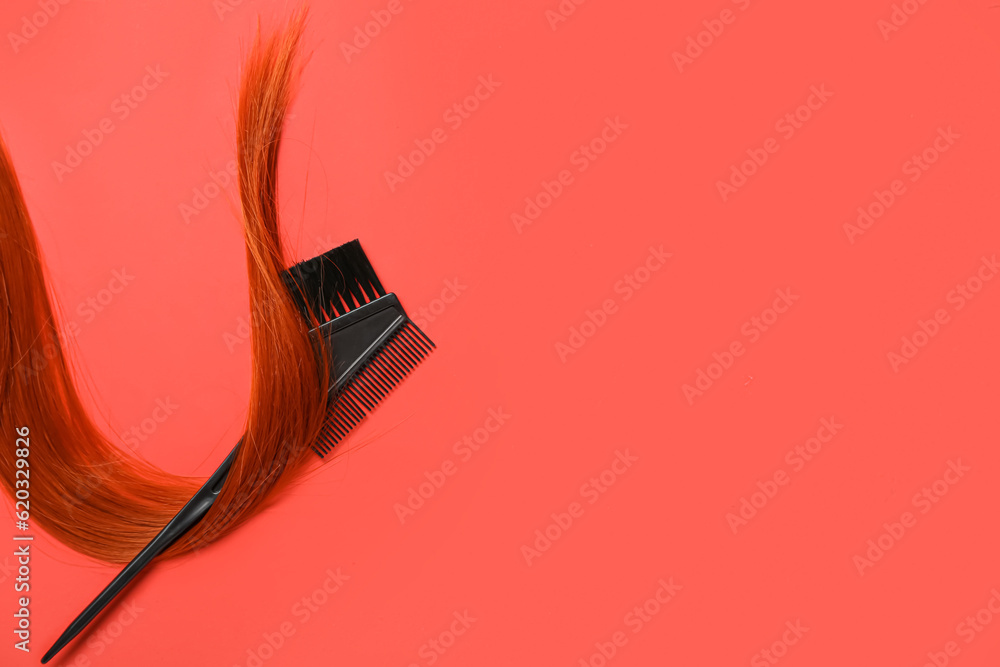 Ginger hair strand and brush on red background